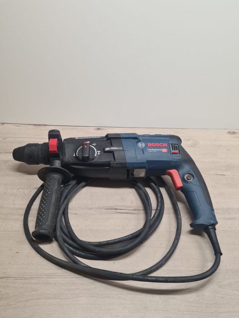 Blau-schwarzer Bosch Professional Bohrhammer mit aufgewickeltem Netzkabel auf einer Werkbank.